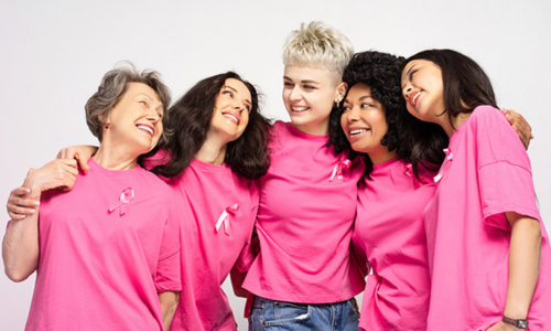 Group of women wearing Pink coloured T-shirts smiling at the camera