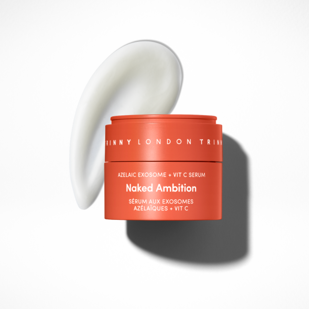 Trinny London Naked Ambition Azelaic Exosome + Vitamin C serum in a coral-orange jar, shown with a white cream smear on a light grey background.