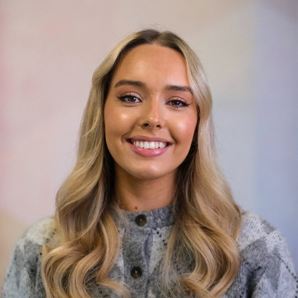 A young female with blonde hair is smiling to camera.