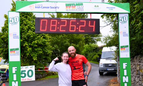 Man and woman cheering the completion of their marathon in front of a fish line sign