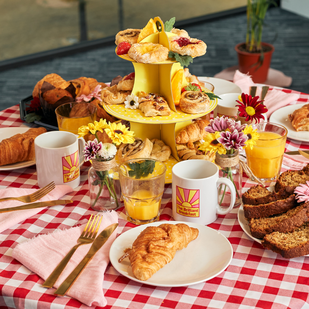 A table set with croissants, mugs and breakfast items.